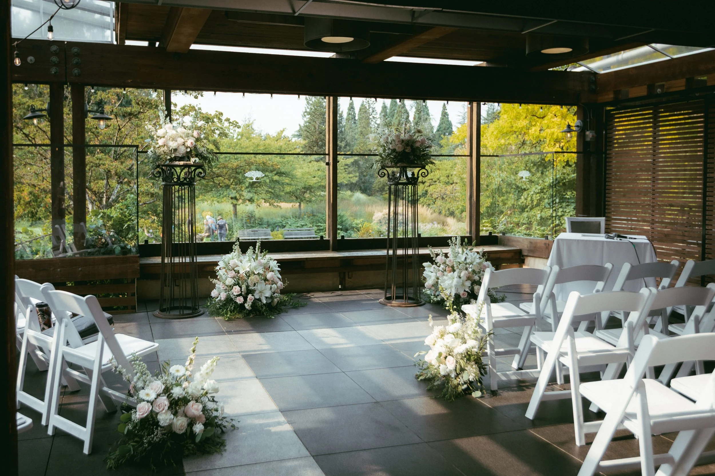 Indoor wedding or event setup with floral arrangements and white chairs.