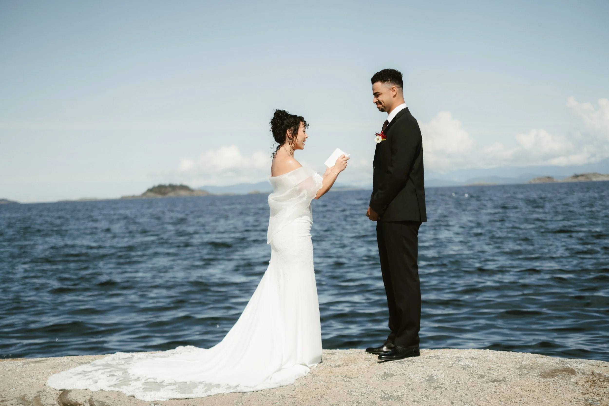 Bride and groom exchanging vows beside the ocean on a sunny wedding day