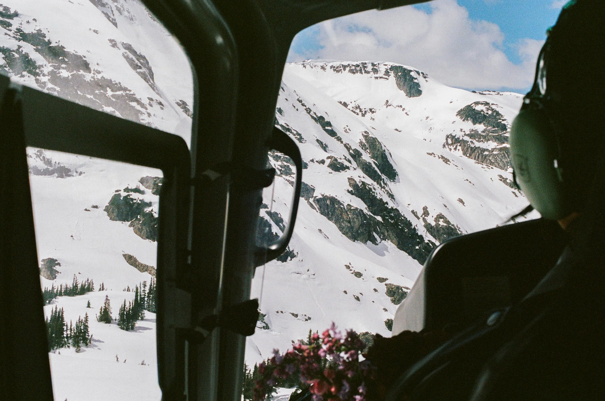 Snow-covered mountains seen through a helicopter window, photographed on 35mm film
