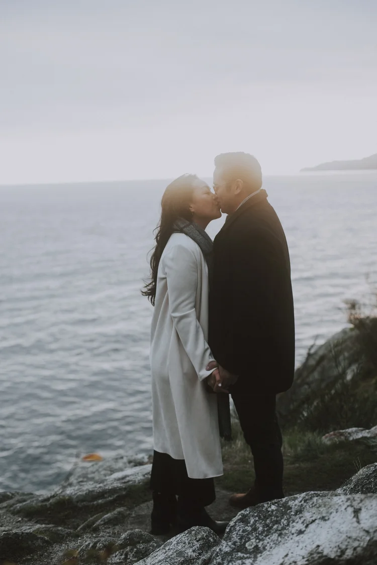 A couple kissing on a rocky cliff above the sea