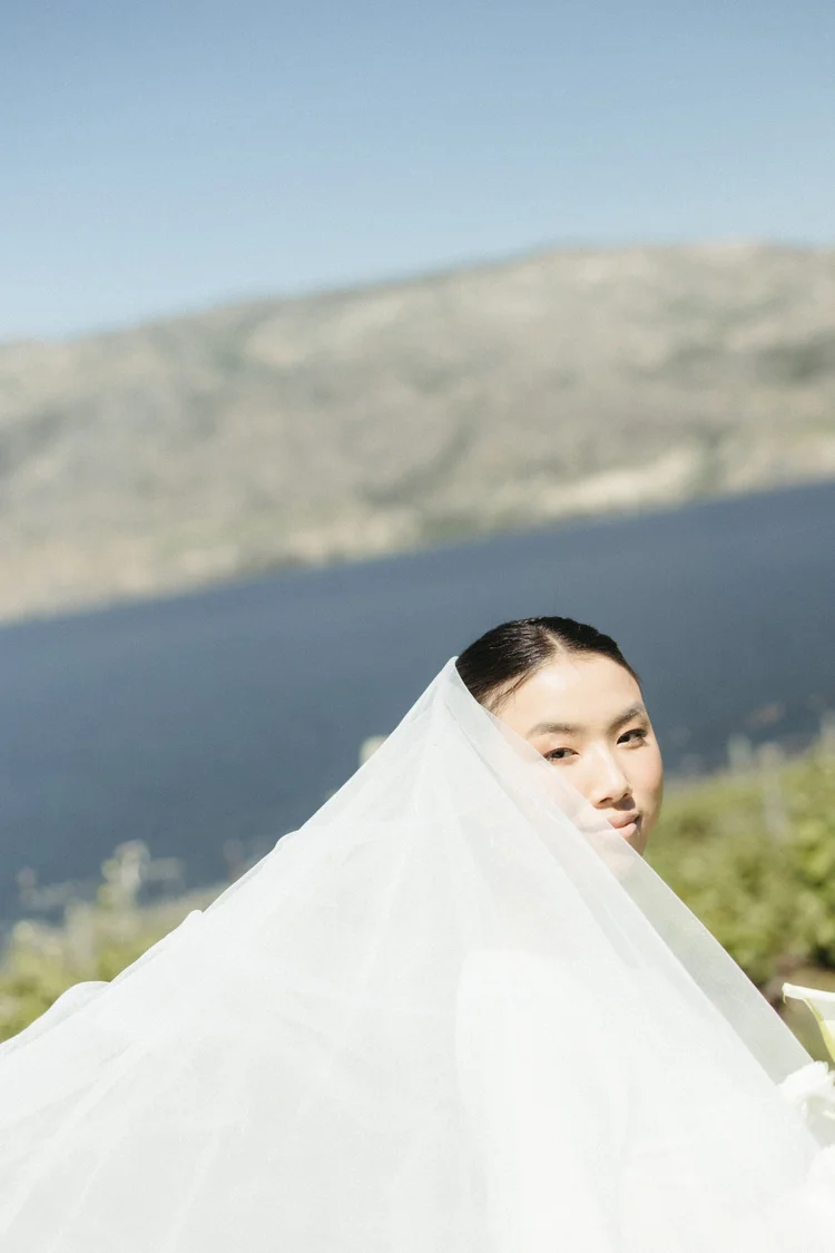A bride&rsquo;s veil lifting across her face above Okanagan Lake