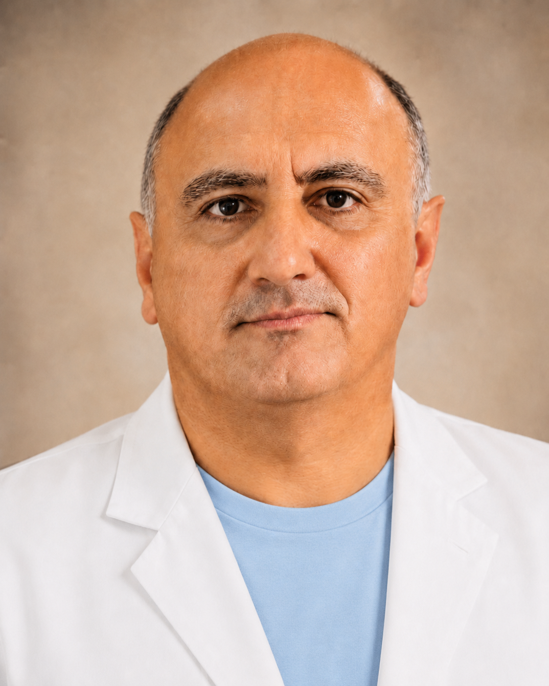 A middle-aged man with a bald head and tan skin, wearing a white coat over a light blue shirt, facing directly toward the camera with a neutral expression.