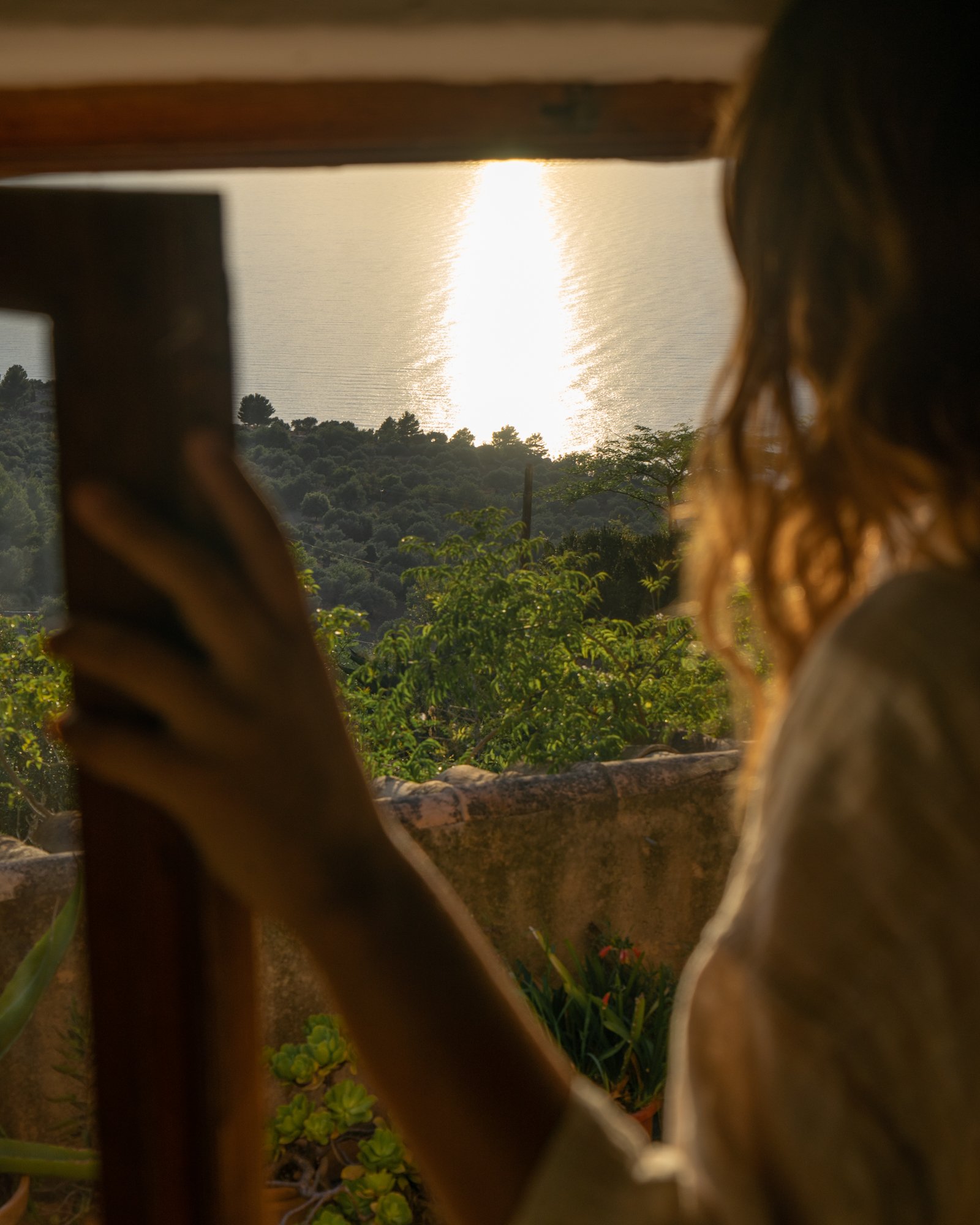 A preson look out the window and see the beautiful sea with sunset