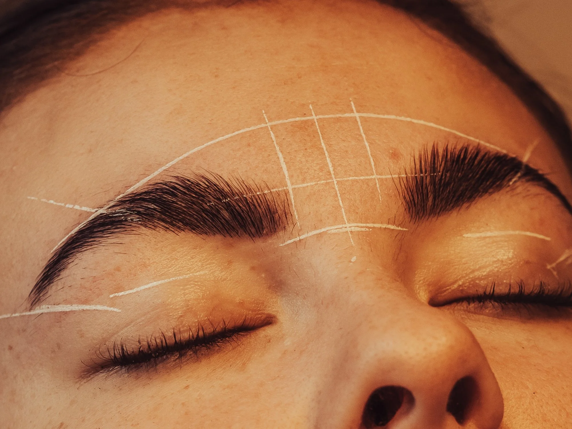 Client relaxing during a brow and lash treatment at BLINK Beauty studio in Renfrew