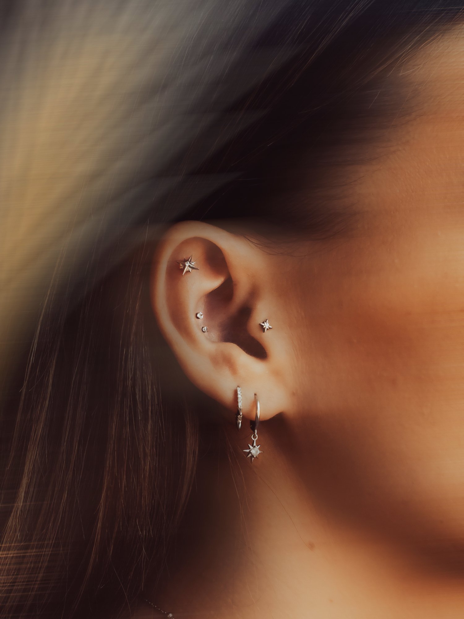 Luxury ear jewellery curation with multiple piercings at BLINK Beauty in Renfrew