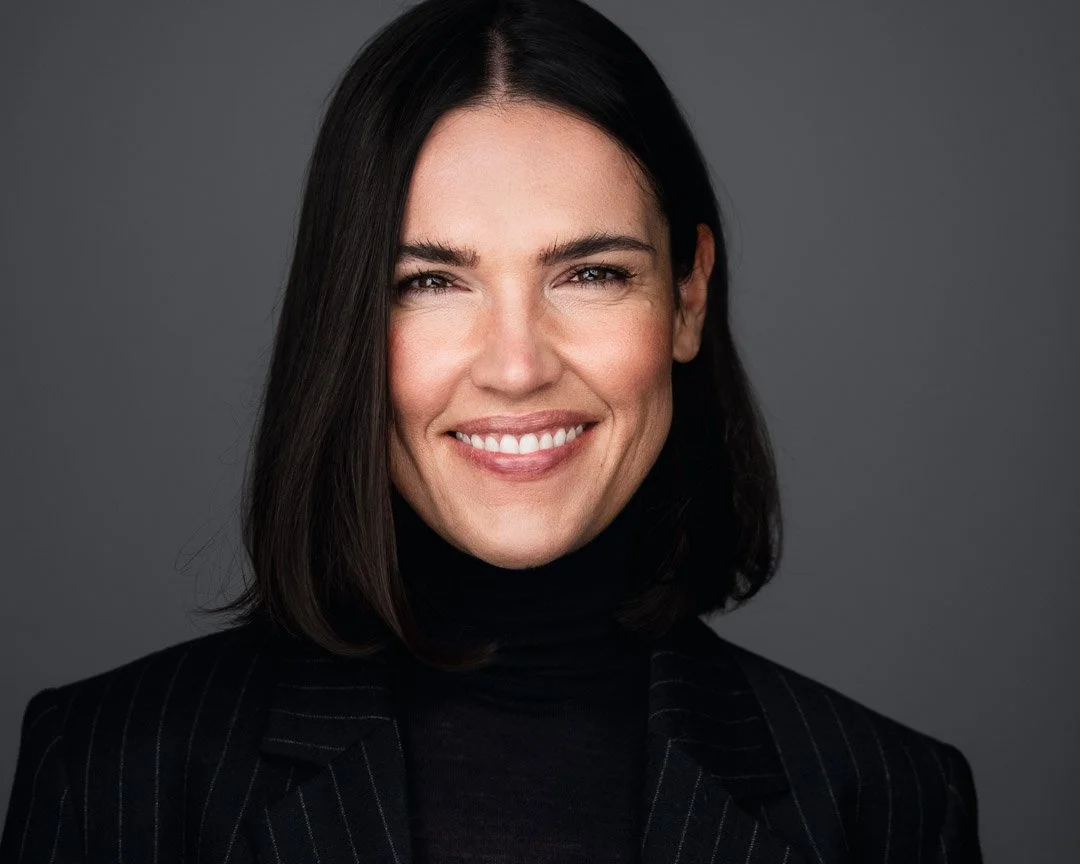 Bewerbungsfoto einer schwarzhaarigen Frau mit schwarzem Blazer und Rollkragen