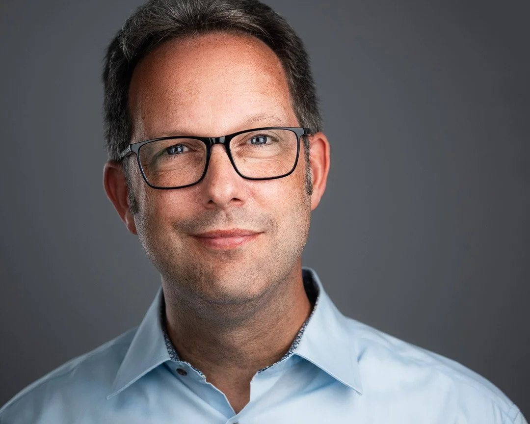 Businessportrait eines Mann mit Brille und blauem Hemd im Fotostudio
