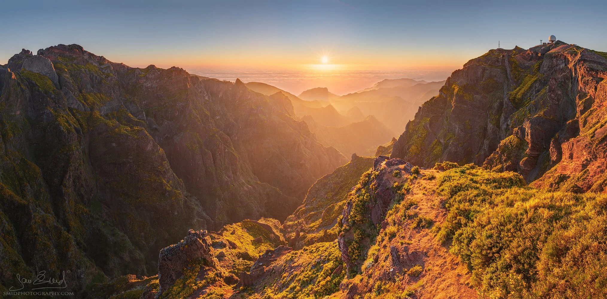 Panoramic landscape photograph "On the Windy Mountain" capturing the first golden rays of sunrise illuminating the volcanic ridges of Pico do Arieiro, Madeira. Captured by Jan Smid, Master QEP, during a 2019 photography expedition.