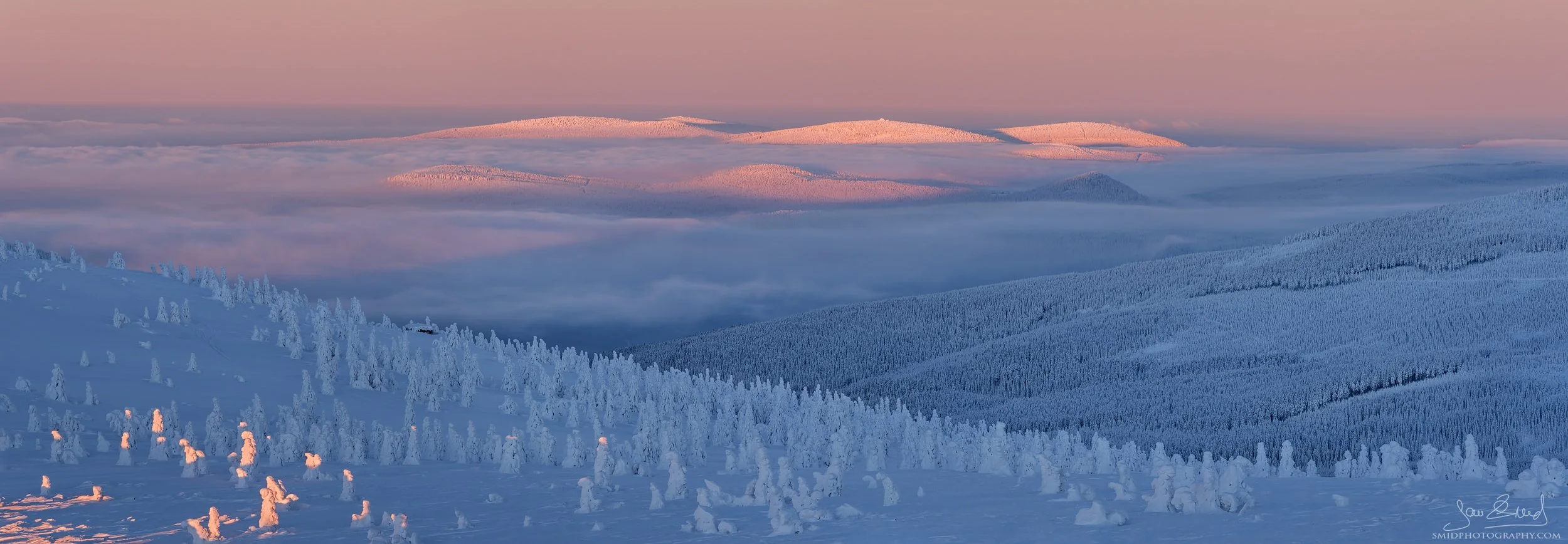 Panoramic winter sunset in the Giant Mountains with a high cloud inversion covering the valleys of Krkonose.