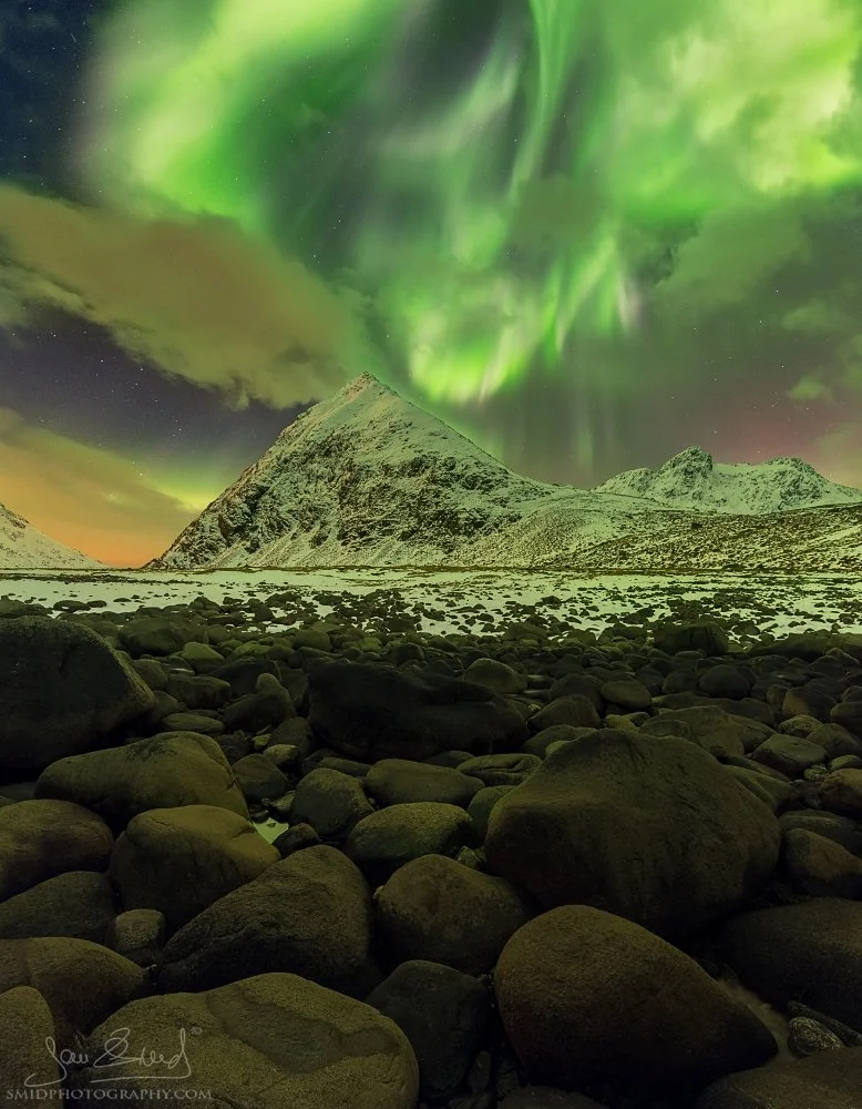 Award-winning panoramic photograph "Pyramid in Green" showing a massive Aurora Borealis over the mountain peaks at Unstad Beach, Lofoten. Captured by Jan Smid, Master QEP, in 2017.