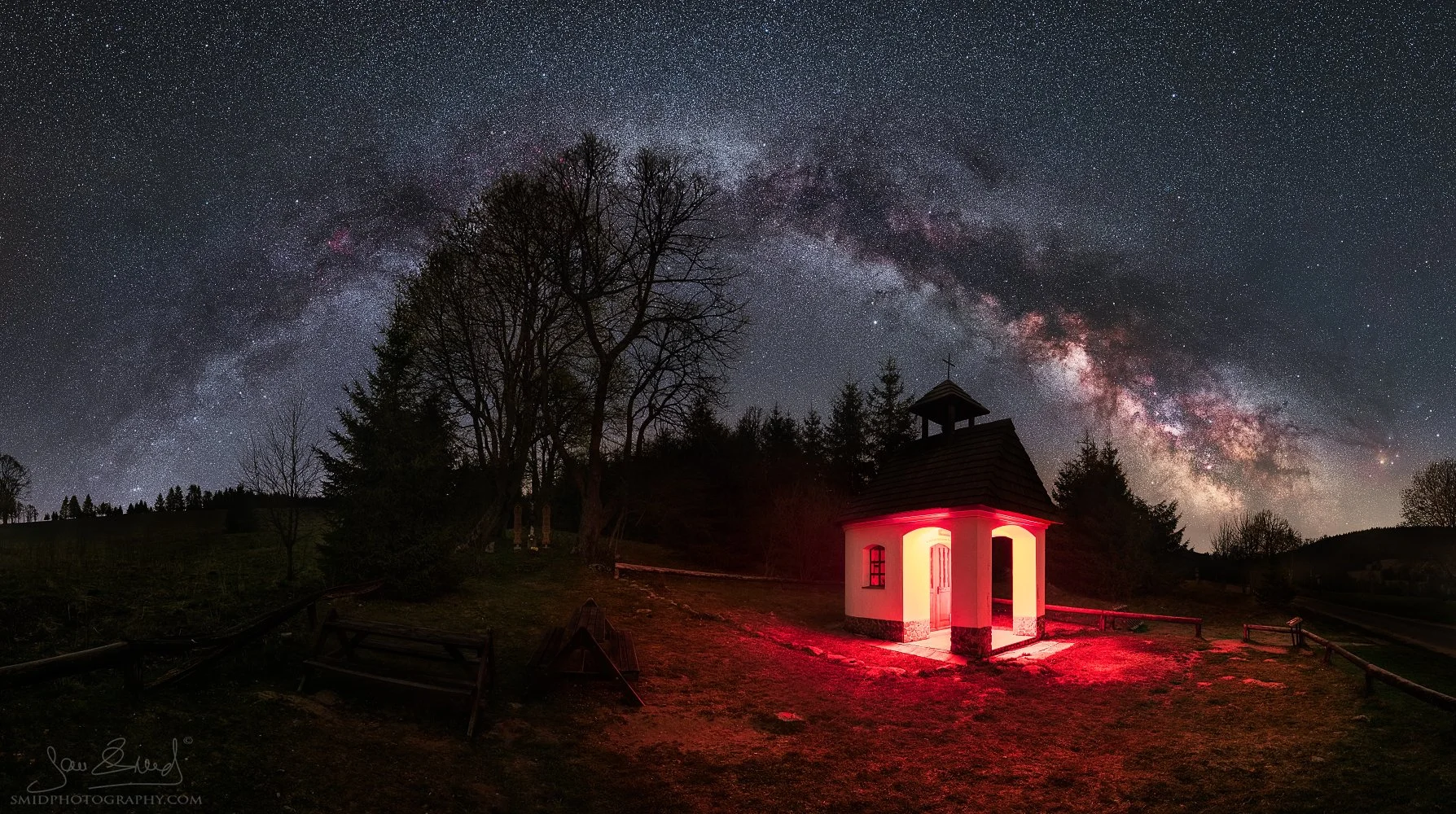 Award-winning panoramic night photography of a full Milky Way arch over a lone chapel in Sumava, titled The Gateway to Hell II, by Jan Smid, Master QEP.