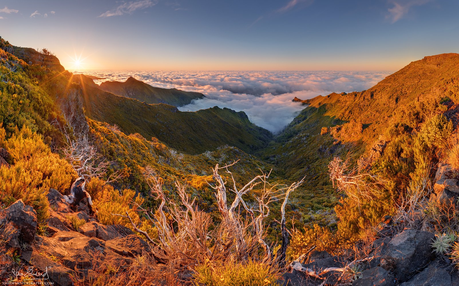 Jan Smid: Dramatic sunset view of Pico Ruivo peaks and foreground rocks in Madeira. Warm light and strong sun starburst. Award-winning photo workshop.