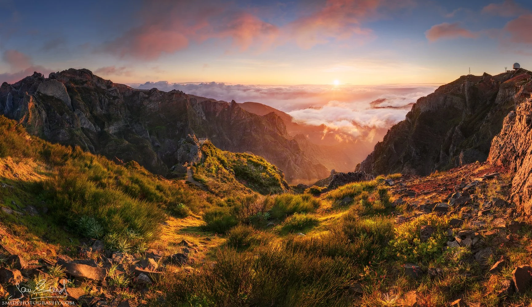 A majestic panoramic landscape photograph "Rhythm of Wind" showing the sun rising over the jagged volcanic ridges and flowing clouds at Pico do Arieiro, Madeira. Captured by Jan Smid, Master QEP, during a 2021 photography expedition.