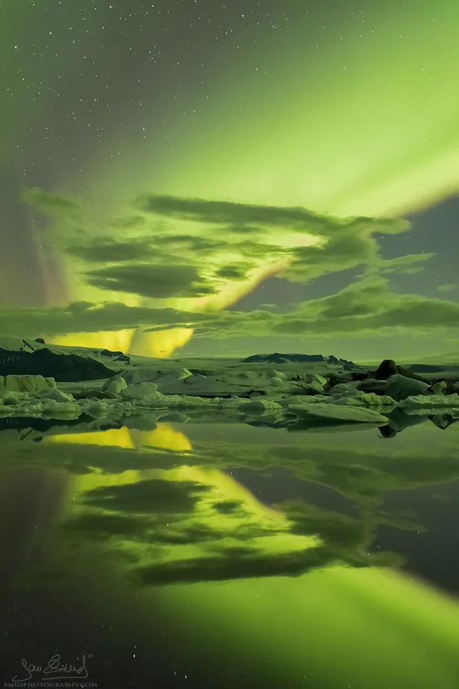 Grand night photo titled "Glacial Aurora Spectacle." A massive Aurora Borealis arch over the icebergs of Jökulsárlón glacier lagoon. Captured by Jan Smid, Master QEP, during a 2015 photo expedition in Iceland. High-end fine art.