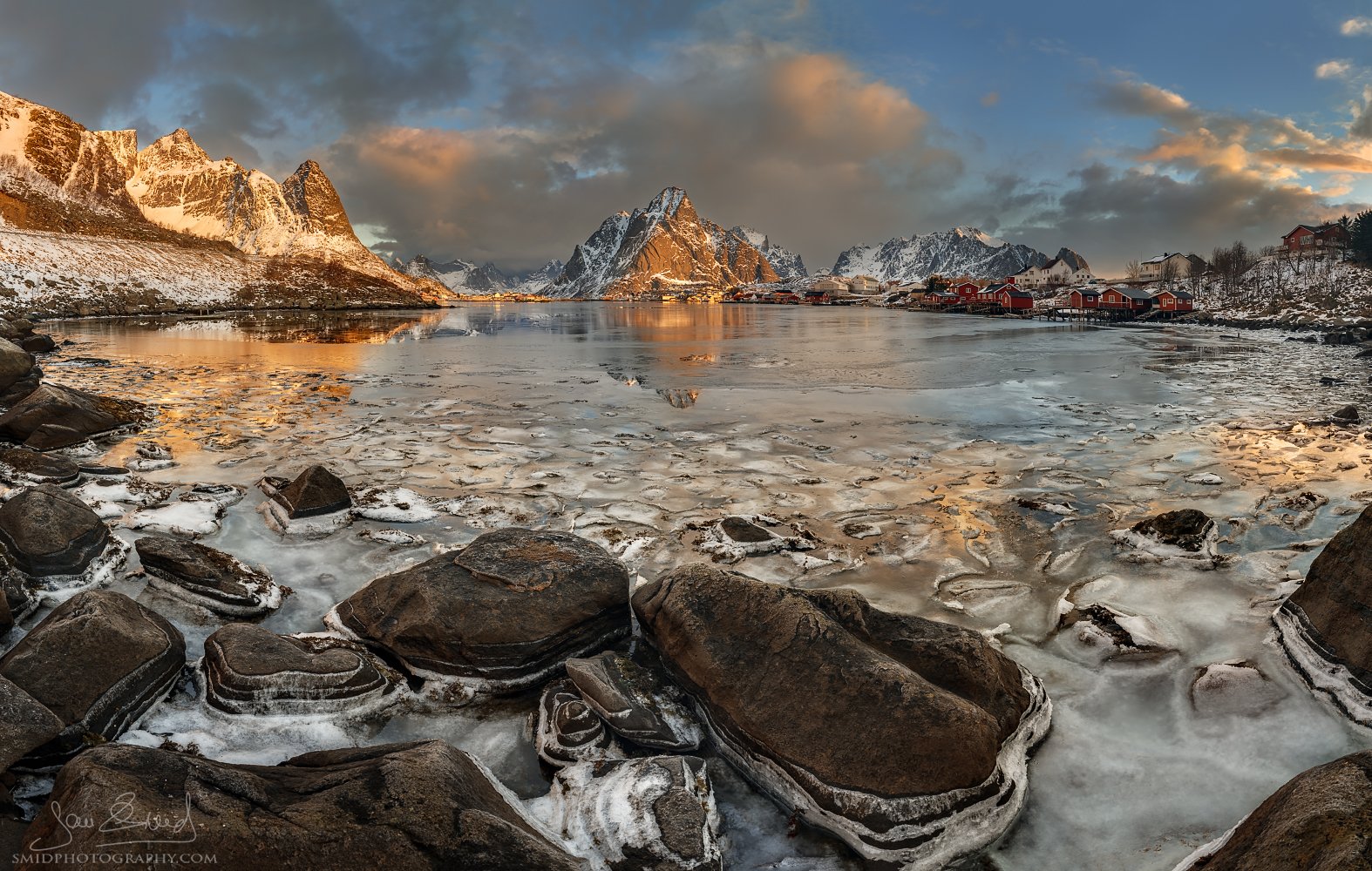 Multi-award-winning panoramic photograph "Frozen Reine" featuring the iconic snow-covered rorbuer huts in Reine, Lofoten Islands. Captured by Jan Smid, Master QEP, in 2018.