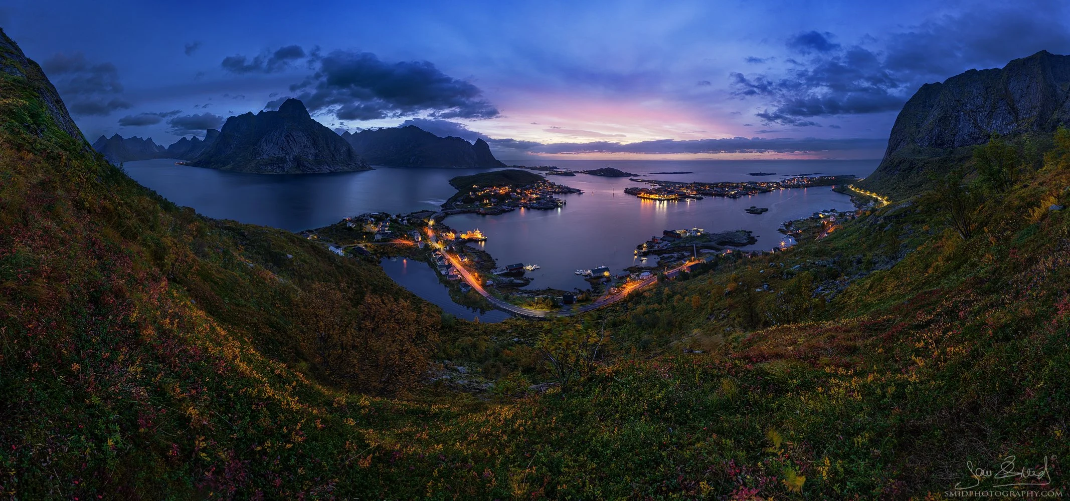 Panoramic autumn photograph "From Above" featuring an exclusive pre-sunrise view of Reine and Hamnøy villages from a unique mountain vantage point. Captured by Jan Smid, Master QEP, in 2023.