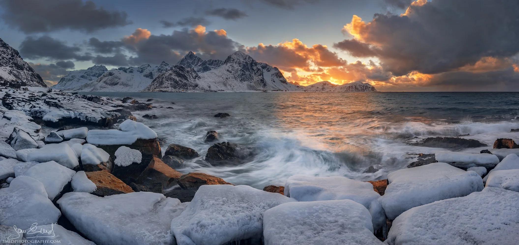Panoramic landscape photograph "Nordic Glaciers" showing snow-covered rocks and a golden sunset over the Lofoten coast. Captured by Jan Smid, Master QEP, in 2018.