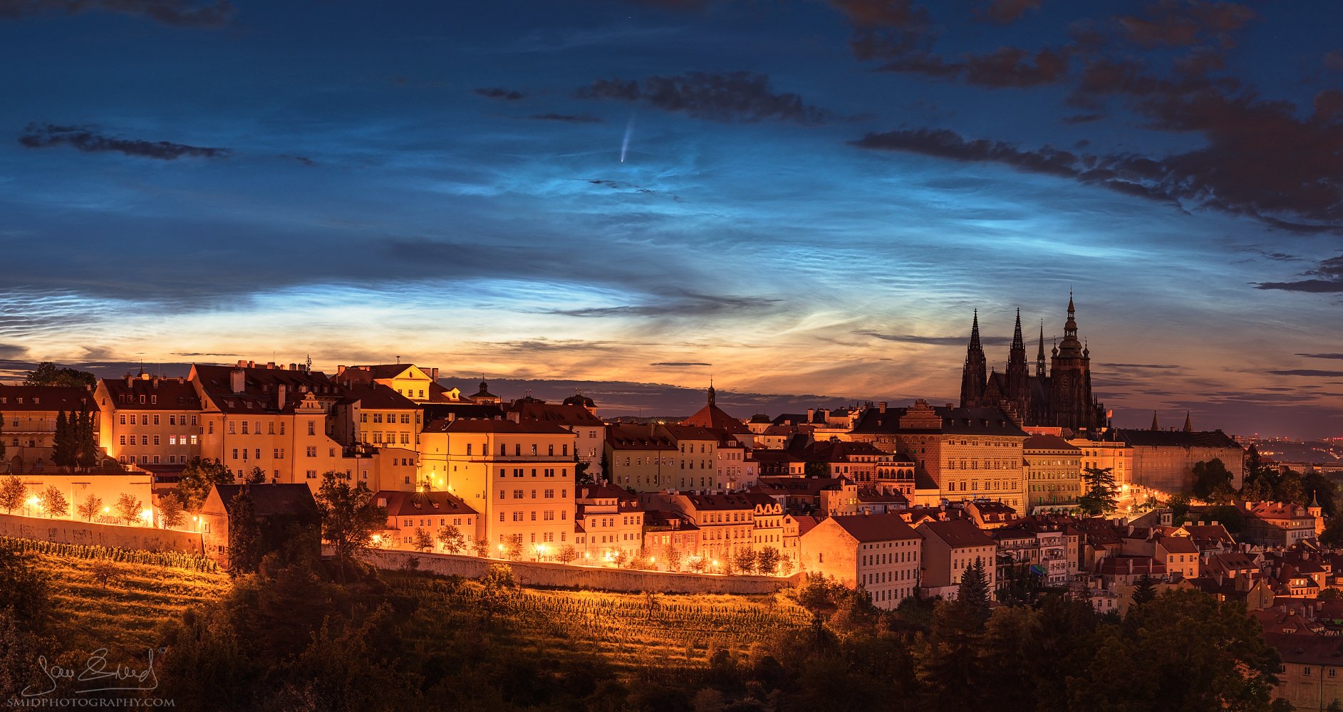 Award-winning astrophotography titled "Comet and the Noctilucent Clouds…above Prague." Rare alignment of Comet NEOWISE and Noctilucent Clouds (NLC) over the Prague skyline. Captured by Jan Smid, Master QEP, in 2020.