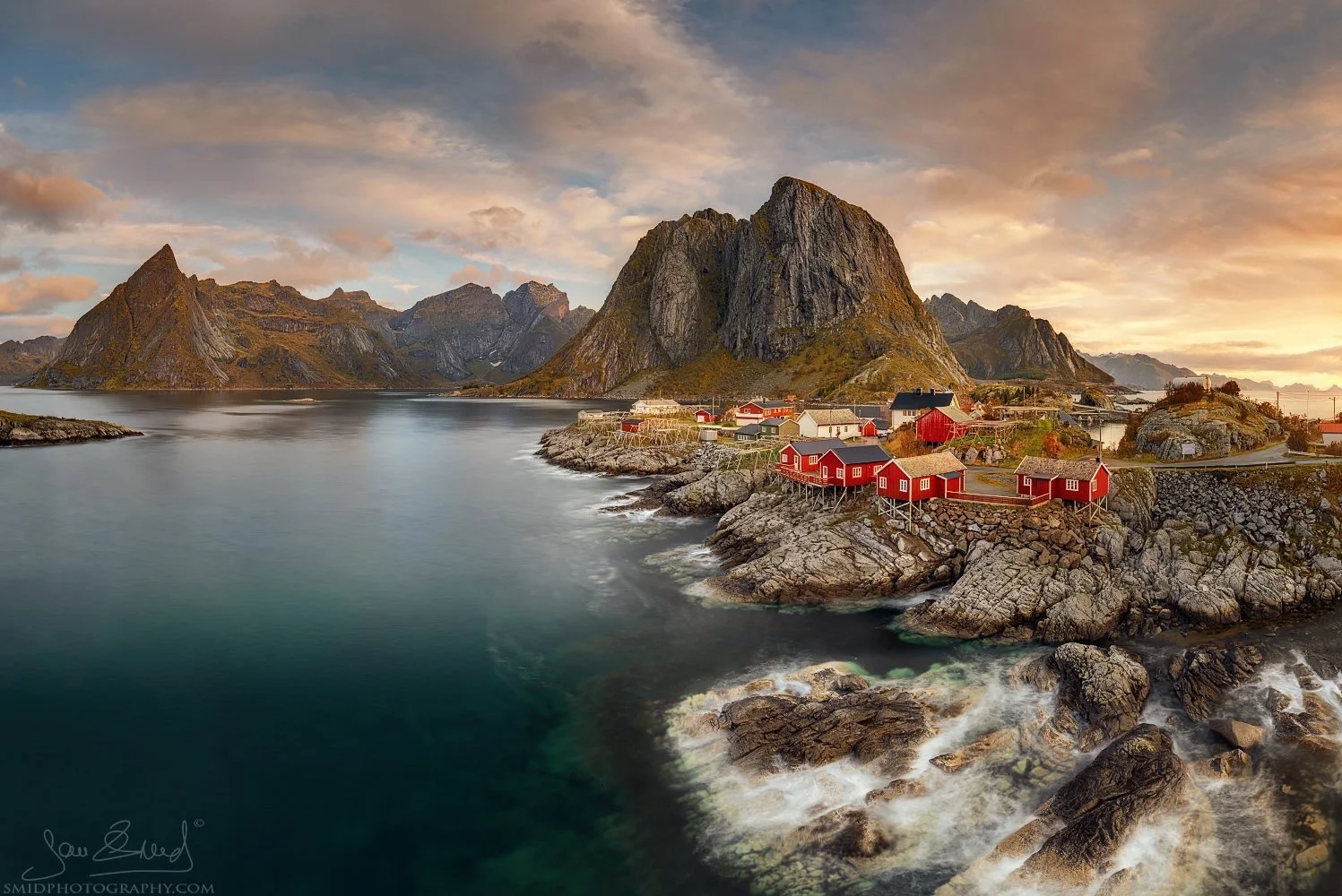 Panoramic autumn view of red fishermen’s cabins in Hamnøy, Lofoten Islands, with dramatic cloud light, captured during Jan Smid’s photo expedition from the classic Reine bridge viewpoint