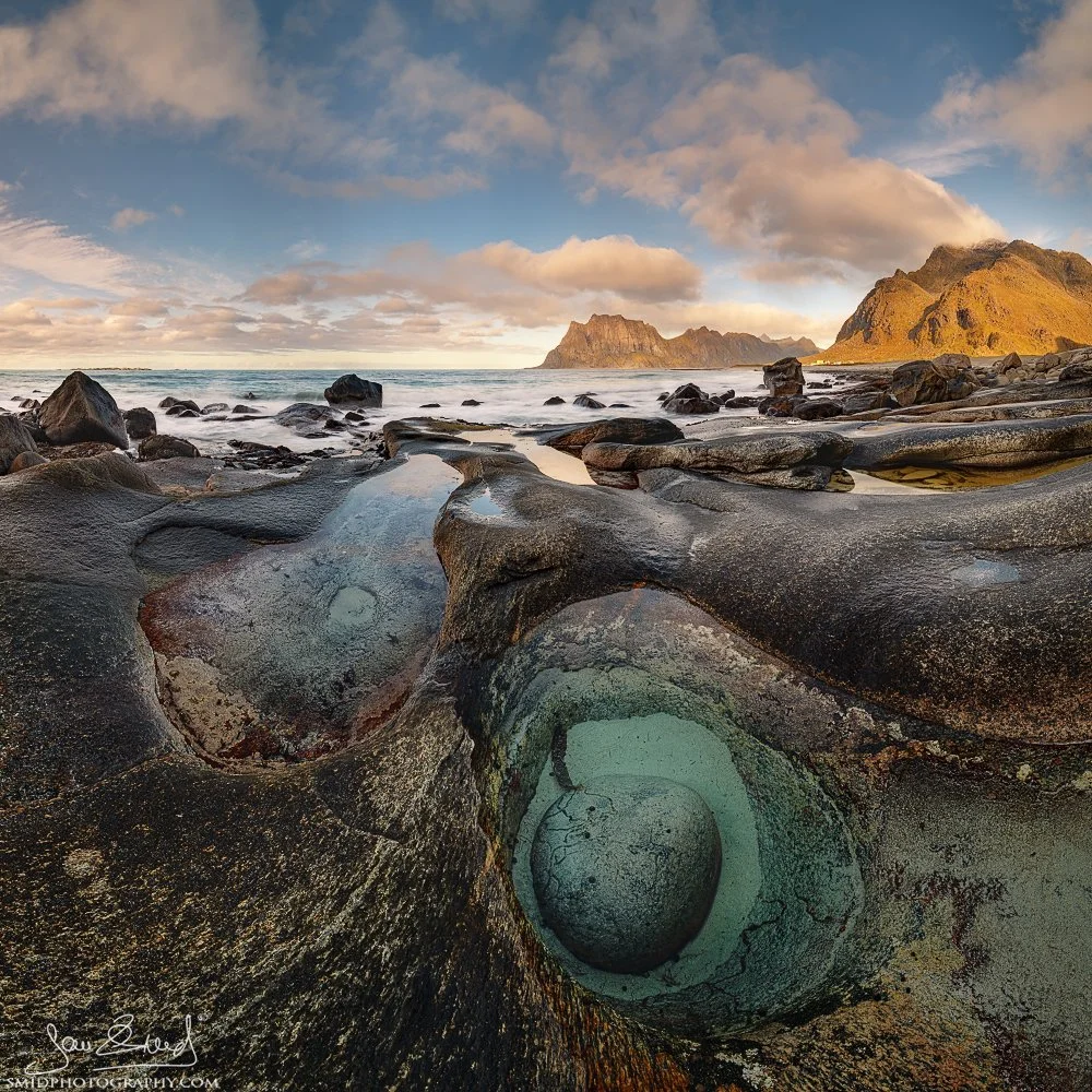Panoramic sunset photograph "A Bowling Ball" featuring a unique circular rock formation filled with water on Uttakleiv Beach, Lofoten. Captured by Jan Smid, Master QEP, in 2020.