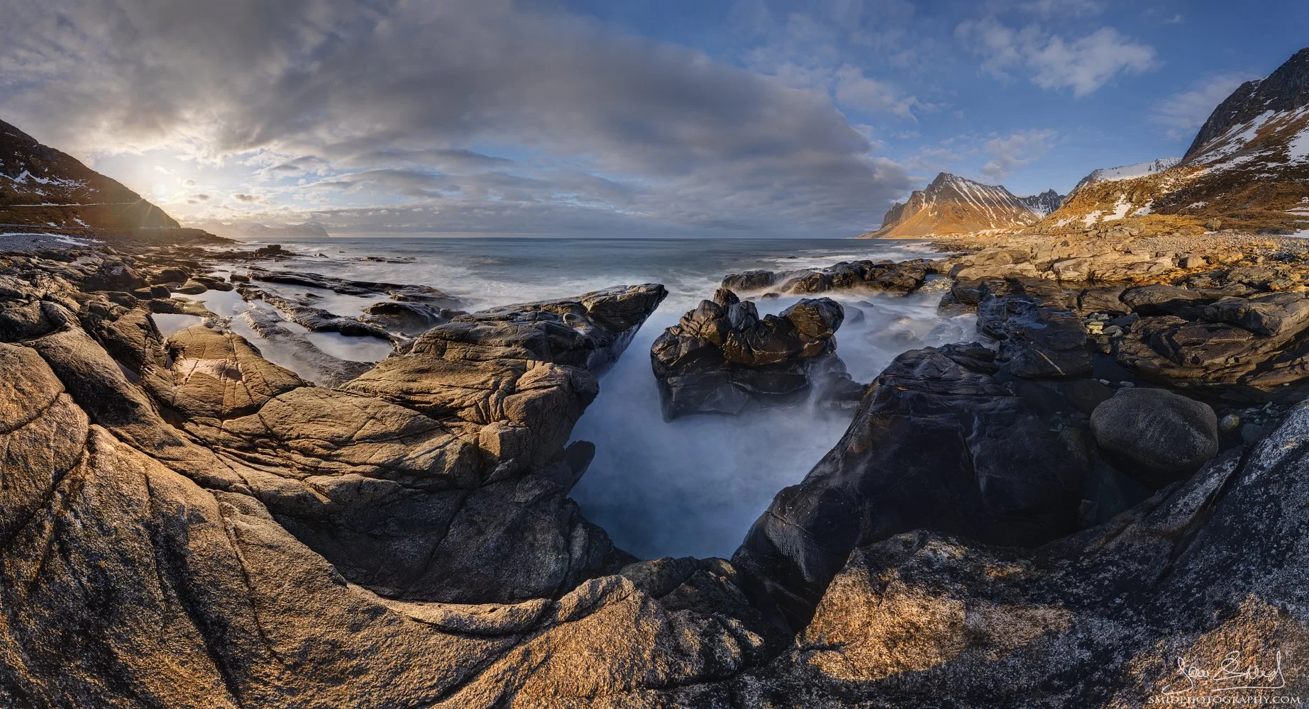 Panoramic landscape photograph titled "Crab Claw" capturing a striking coastal rock formation against the fiery sky of a Lofoten sunset. Captured by Jan Smid, Master QEP, in 2024.
