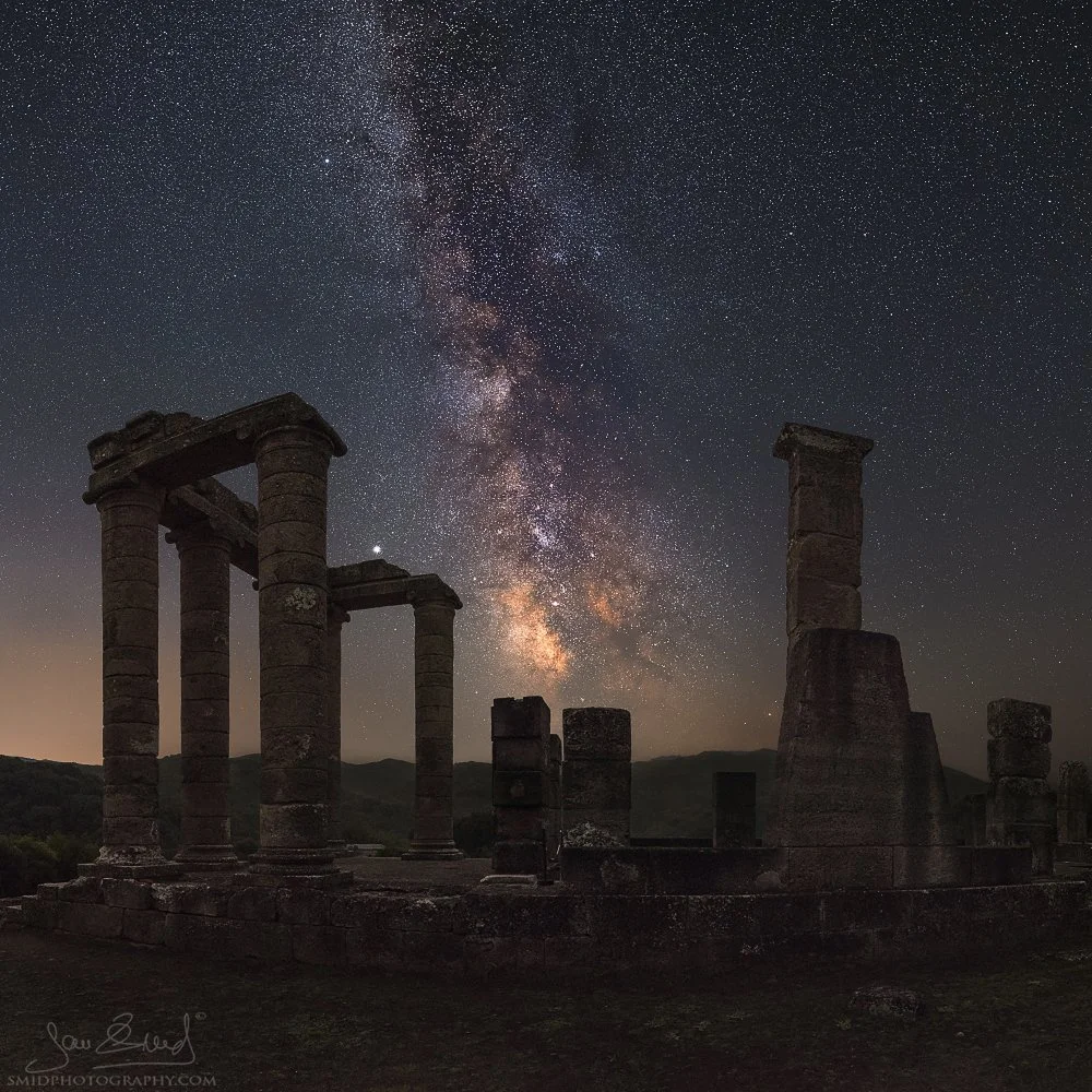 Fine art night landscape photography titled "Relic of the Past." The Milky Way galaxy rising above ancient Roman temple ruins at a secret location in Sardinia. Captured by Jan Smid, Master QEP, in 2020. Square format.