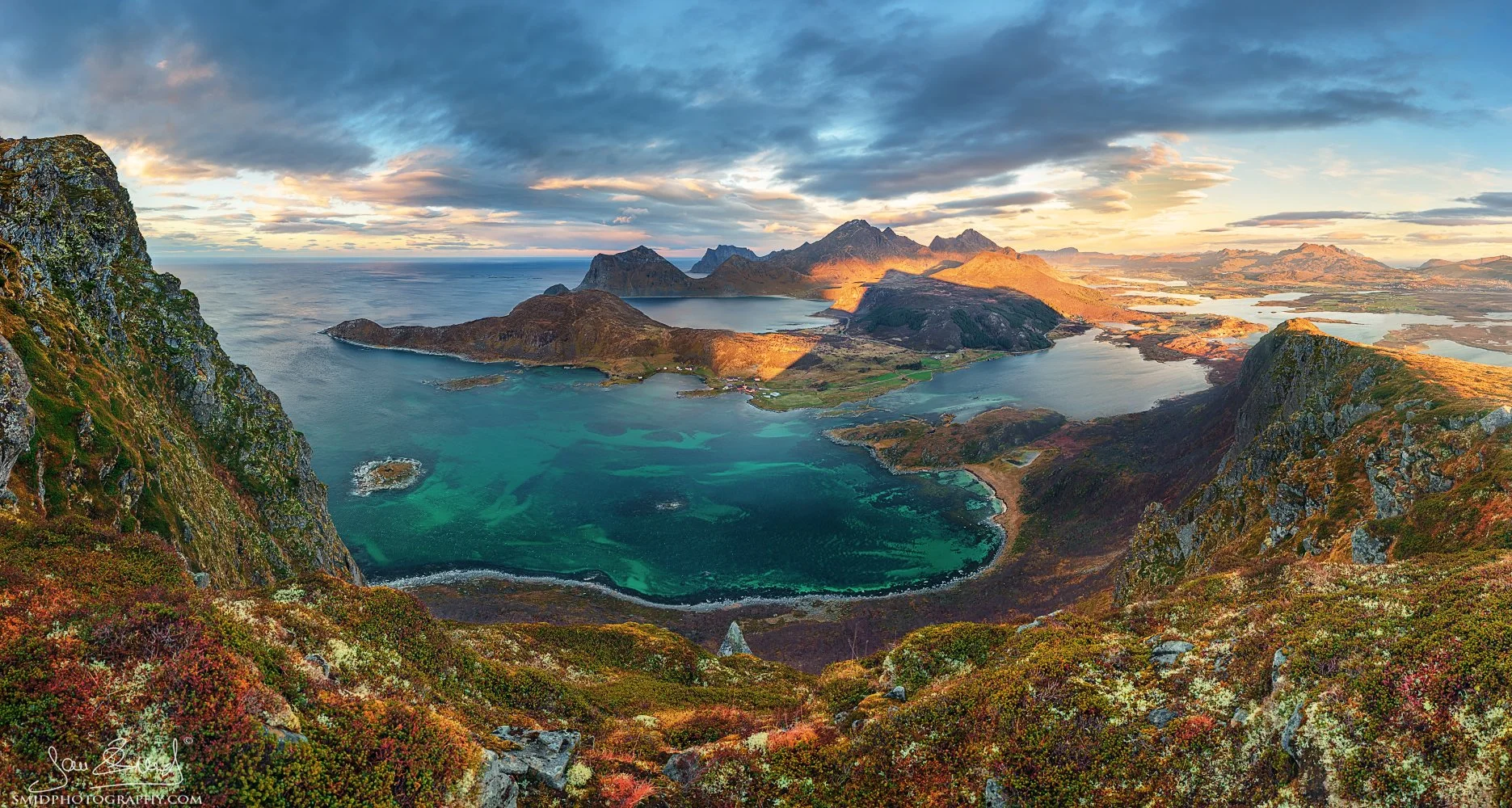 Panoramic landscape photograph "In the Shadow of the Pyramid" featuring autumn colors and turquoise waters from a high mountain peak in Lofoten. Captured by Jan Smid, Master QEP, in 2018.