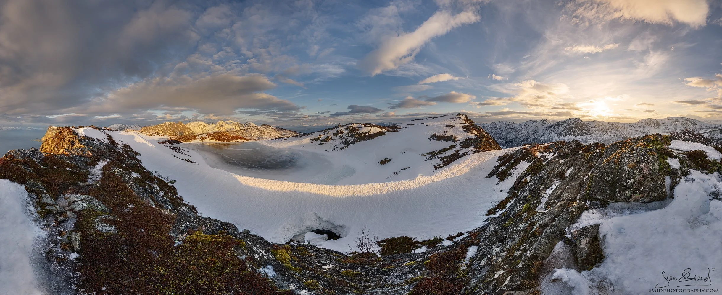 Panoramic landscape photograph "Frozen" capturing a 220-degree view of frozen arctic lakes and mountain peaks during a golden sunset in Lofoten. Captured by Jan Smid, Master QEP, in 2023.