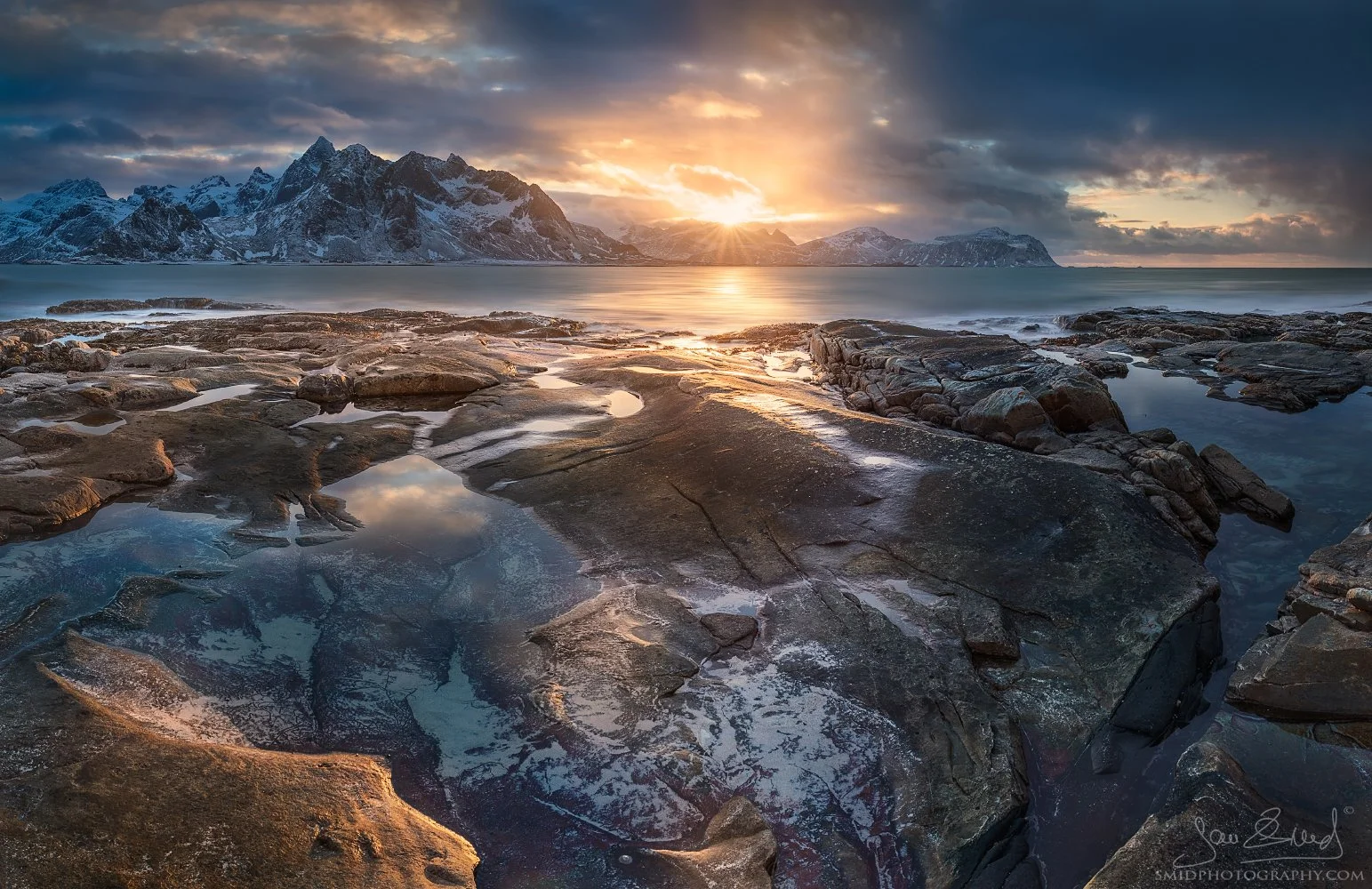 Winter seascape panorama with snowy mountains and golden light just before sunset during photo expedition