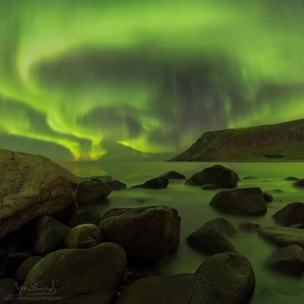 Square panoramic photograph "Drills" capturing vertical Aurora Borealis pillars over the rocky Unstad beach. Professional night landscape by Jan Smid, Master QEP, 2017.