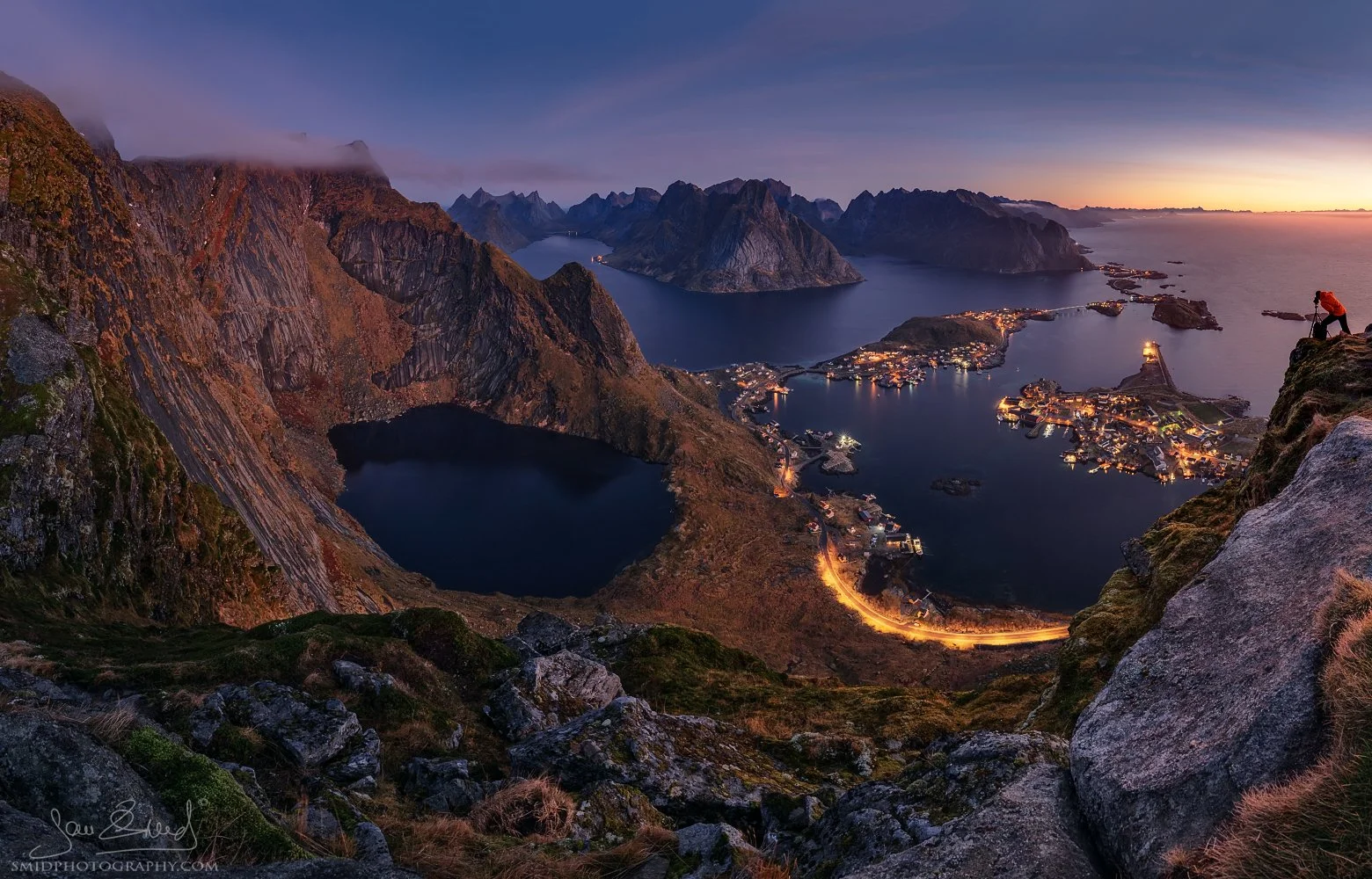 Multi-award-winning night panoramic photograph "Lights in the Sea" showing the illuminated village of Reine from the Reinebringen viewpoint. Captured by Jan Smid, Master QEP, in 2018.