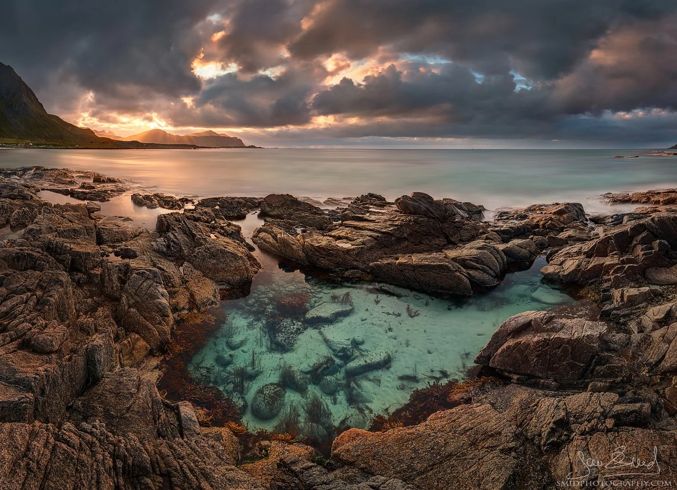 Award-winning panoramic photograph "Fish Out of Water" showing a vibrant Aurora Borealis reflection and tiny boats on the arctic beach of Lofoten. Captured by Jan Smid, Master QEP, in 2019.