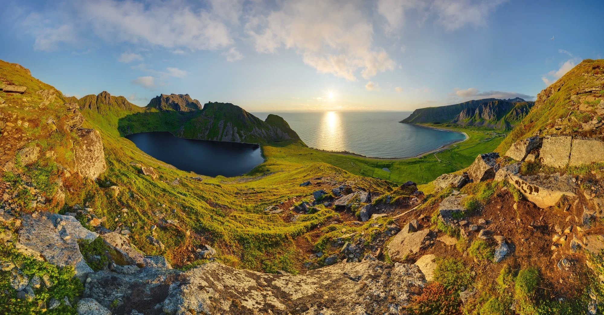 Lofoten seascape during midnight sun with sunset, green foreground, and mountains.