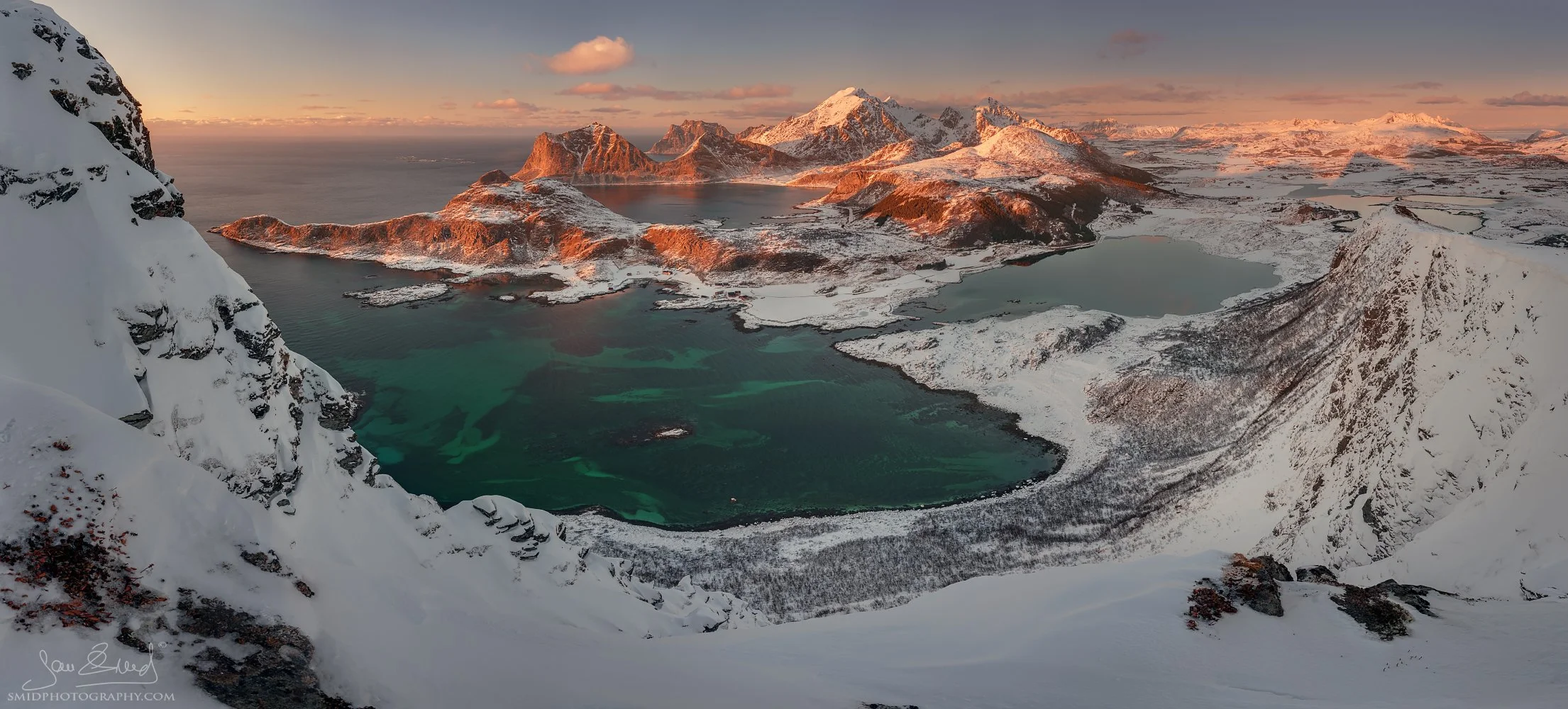 High-altitude panoramic photograph "Norwegian Caribbean" overlooking the turquoise bays of Haukland and Vik, with Veggen and Mannen peaks in the distance. Captured by Jan Smid, Master QEP, in 2018.