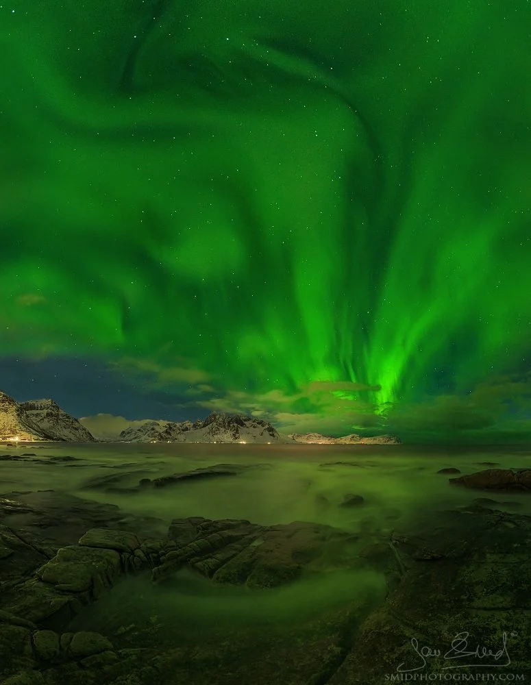 Vertical panoramic photograph "Green Eruption" showing a powerful burst of Aurora Borealis rising like an explosion over the Arctic mountains in Lofoten. Captured by Jan Smid, Master QEP, in 2022.
