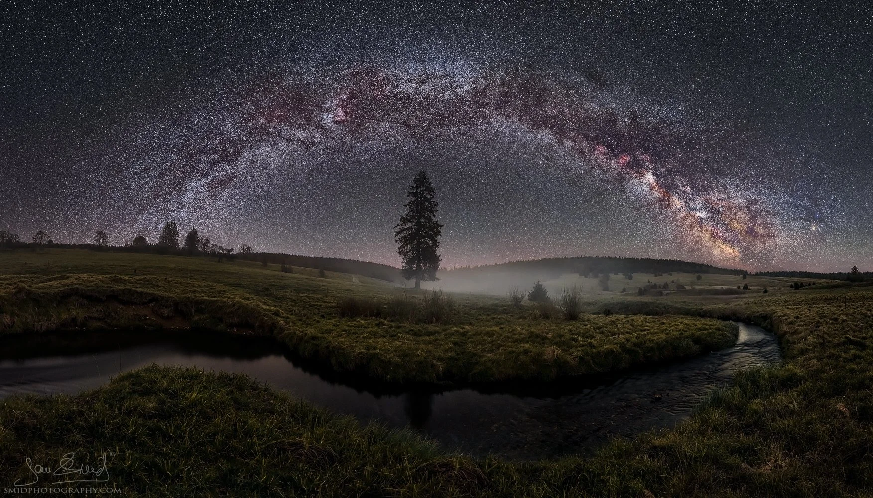 Award-winning night panorama of a full Milky Way arch over a solitary chapel in Sumava, titled Under the Milky Way Arc, by Jan Smid, Master QEP.