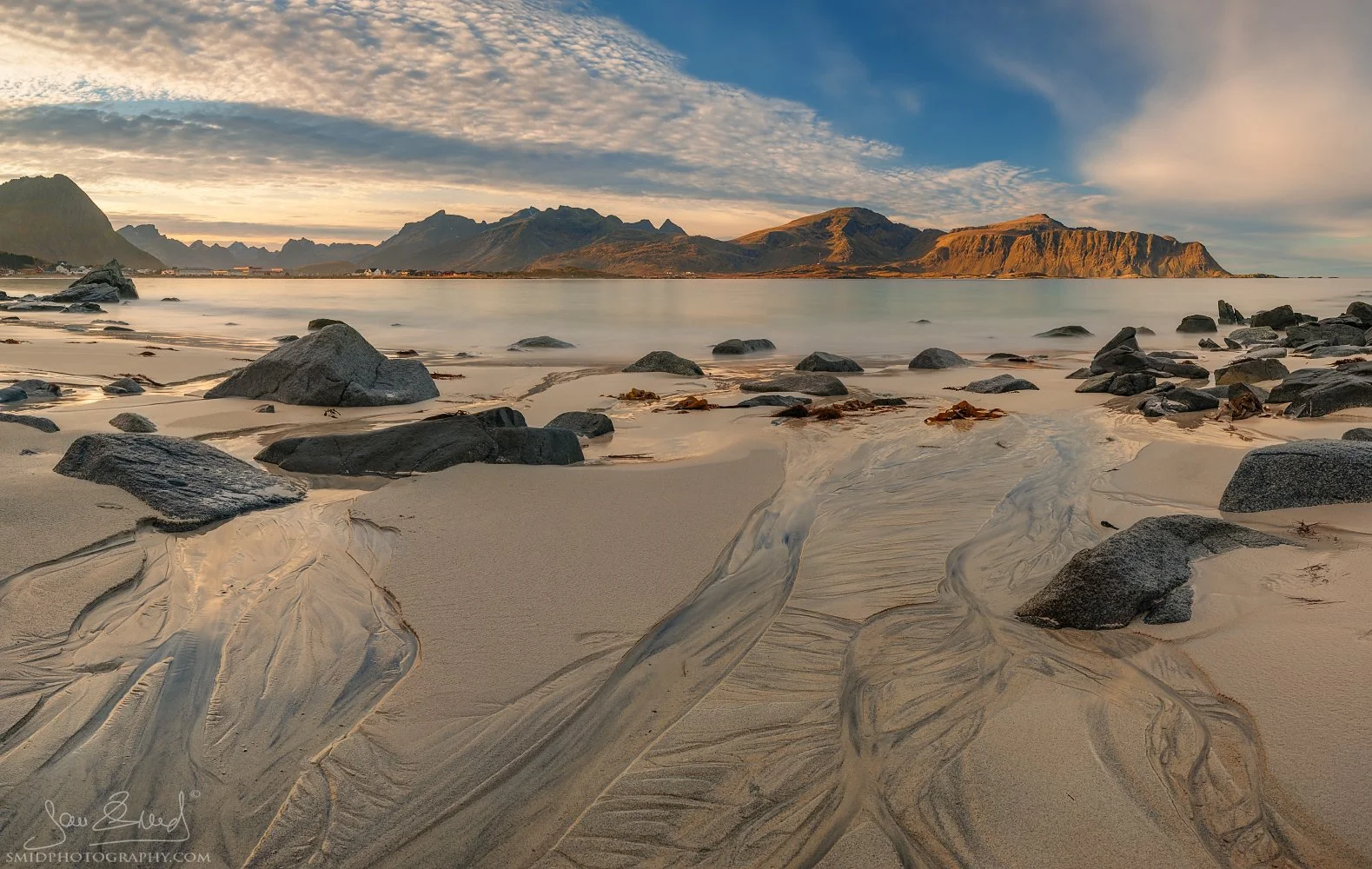 Panoramic landscape photograph "Sources of Life" featuring intricate water patterns in the sand at Ramberg Beach, Lofoten. Captured by Jan Smid, Master QEP, in 2018.
