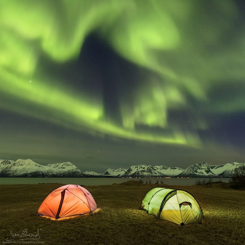 Multi-award-winning Aurora Borealis over illuminated tents in Lofoten by Jan Smid, Master QEP. A hallmark of our long-standing Lofoten Photo Expeditions since 2016.