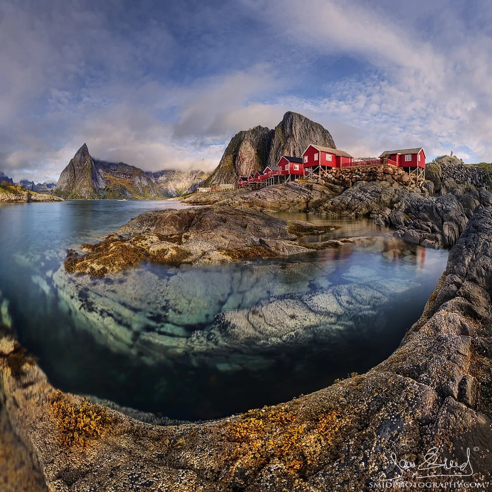 Multi-award-winning panoramic photograph "From a Different Perspective" showing a unique low-angle view of the iconic red cabins in Hamnøy during autumn. Captured by Jan Smid, Master QEP, in 2023.