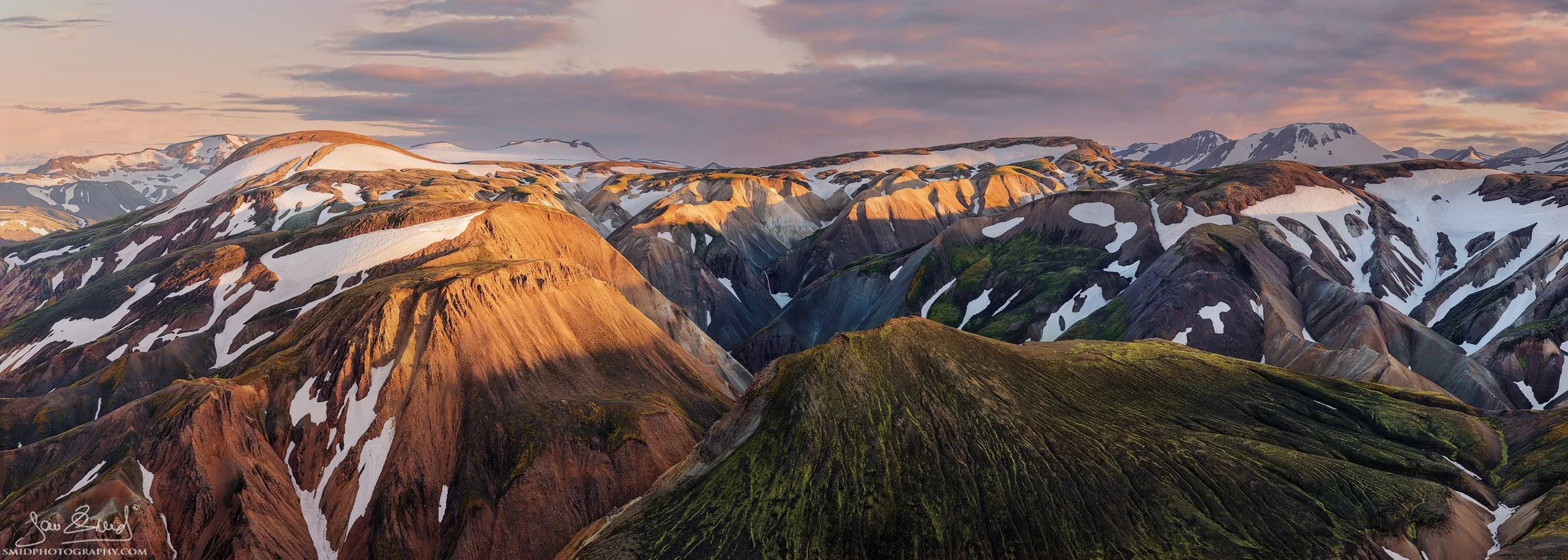 Spectacular sunset panorama titled "On the Mountain Peaks" in Landmannalaugar, Iceland. Colorful rhyolite mountains illuminated by warm evening light. Captured by Jan Smid, Master QEP, during a 2015 photo expedition. High-end landscape art.