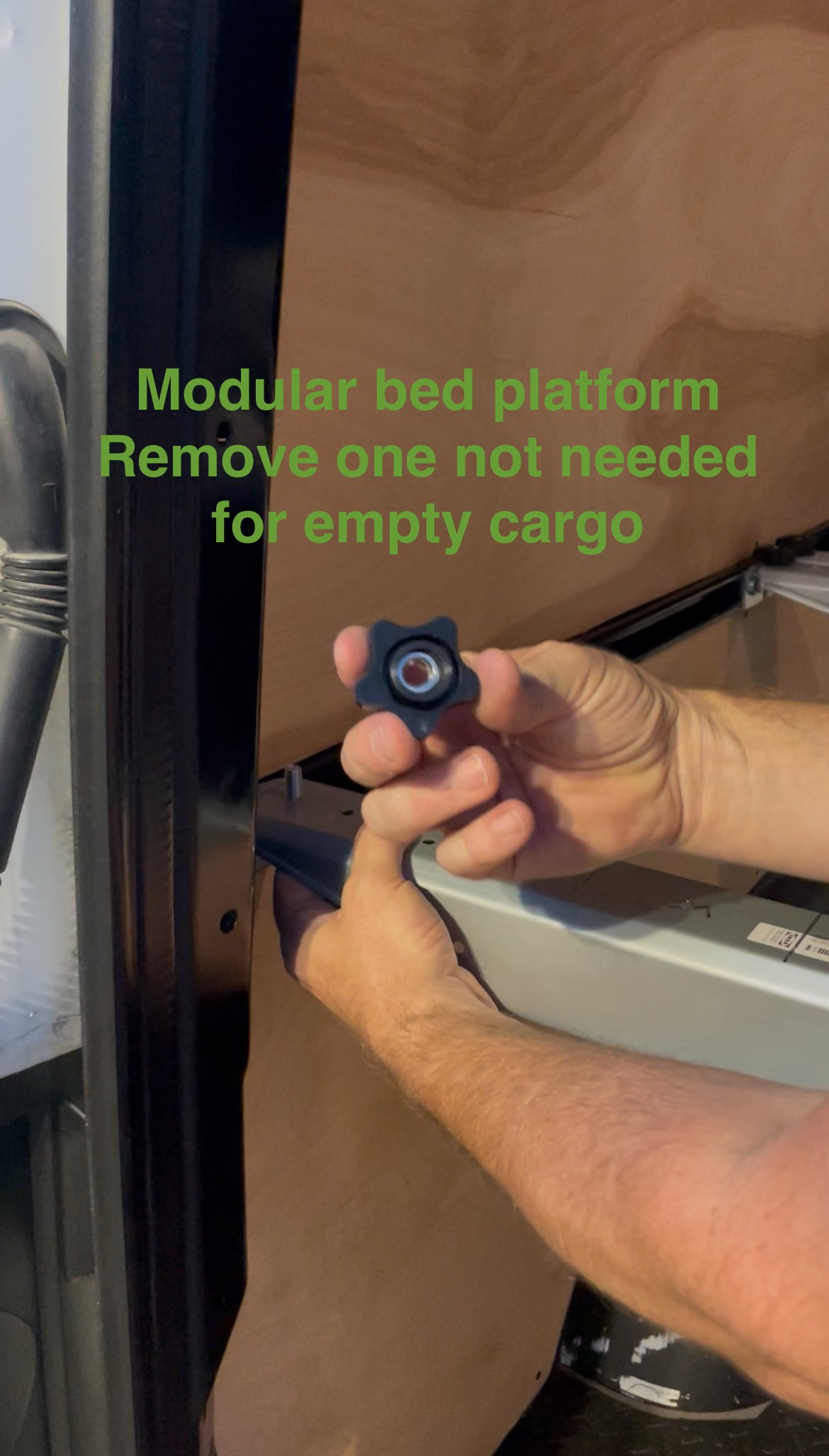 Person removing a modular bed platform support piece from a wooden bed frame.