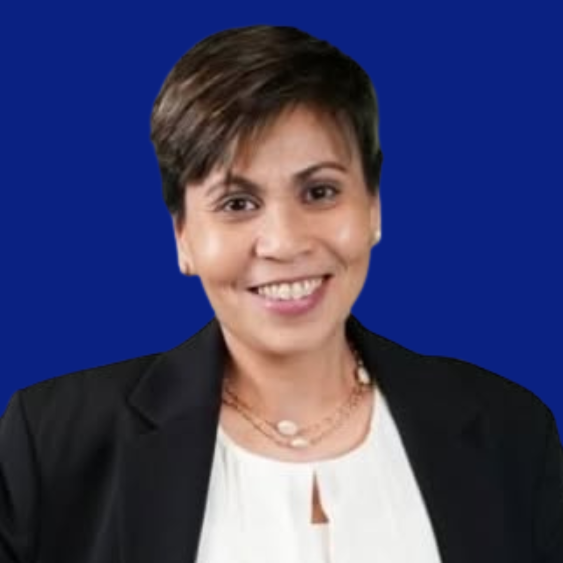 A woman with short dark hair wearing a black blazer and white top smiling against a solid blue background.