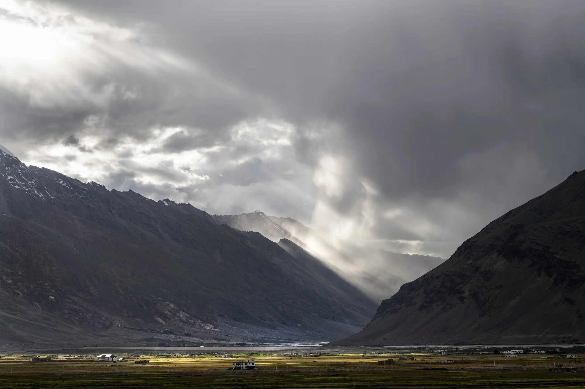 Licht bricht durch die Wolken über dem weiten Zanskar-Tal