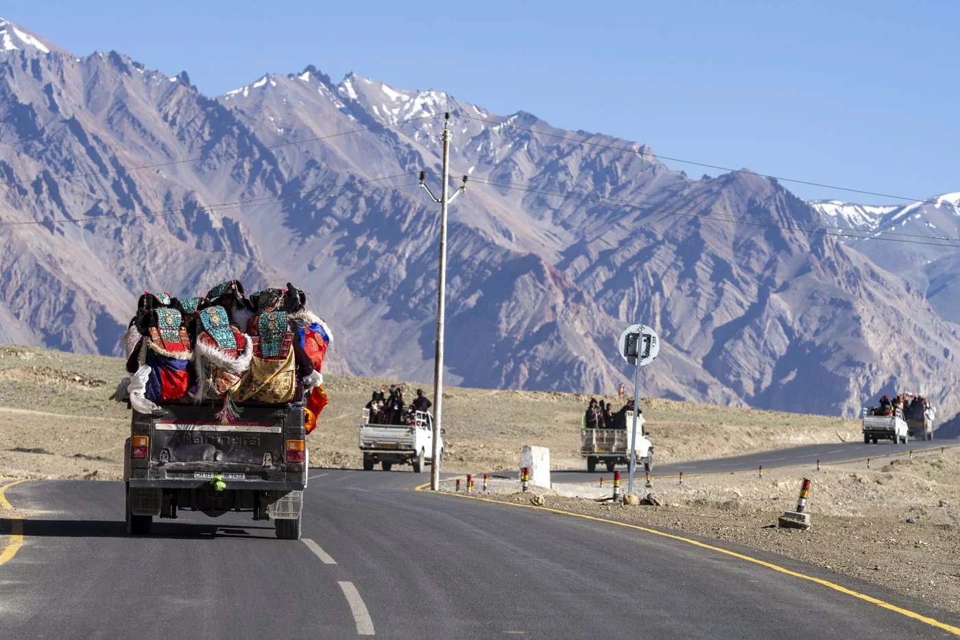 Pickups mit Frauen in Festtracht auf dem Weg zum Empfang eines Lama, Ladakh