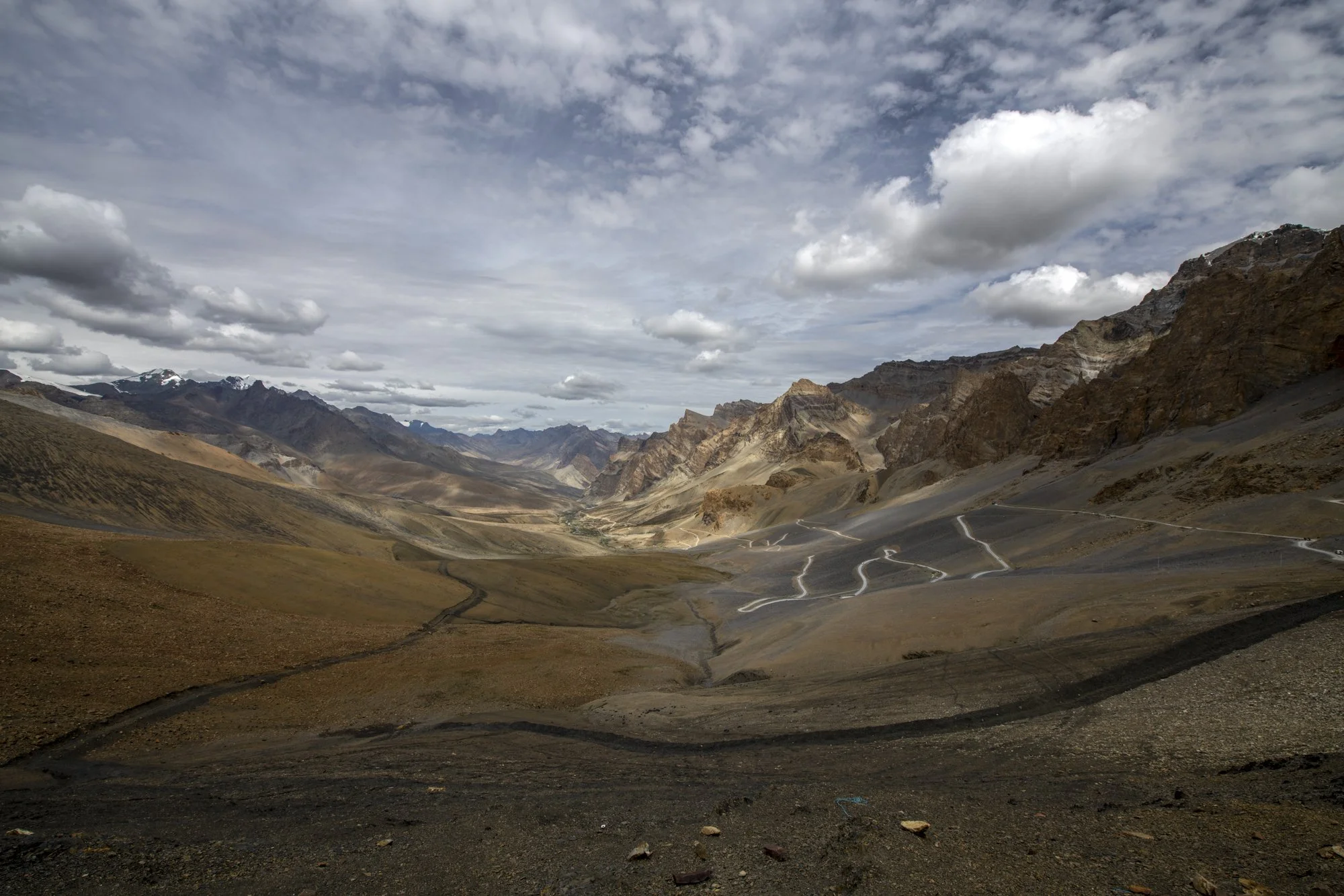 Serpentinen der Passstrasse am Singey La, dahinter ein weites Tal mit Schneebergen, Ladakh