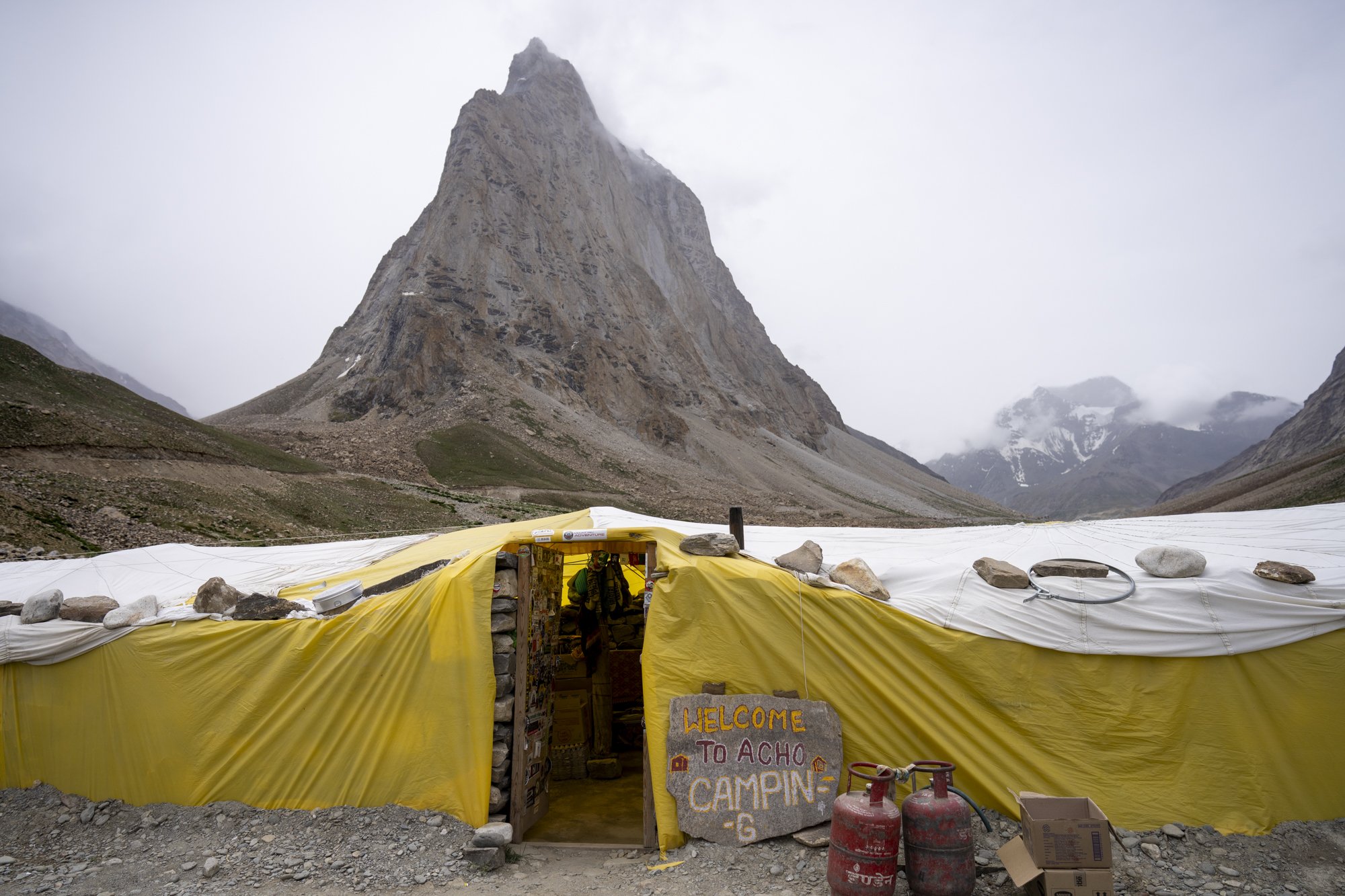 Zeltcamp «Acho Camping» am Weg zum Shingo La, dahinter ein Felsgipfel in Wolken
