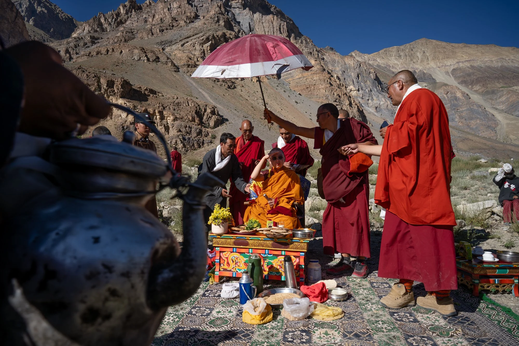 Kyabje Stakna Rinpoche unter zeremoniellem Schirm, umgeben von älteren Mönchen, beim Sani-Gustor-Fest in Zanskar, Ladakh
