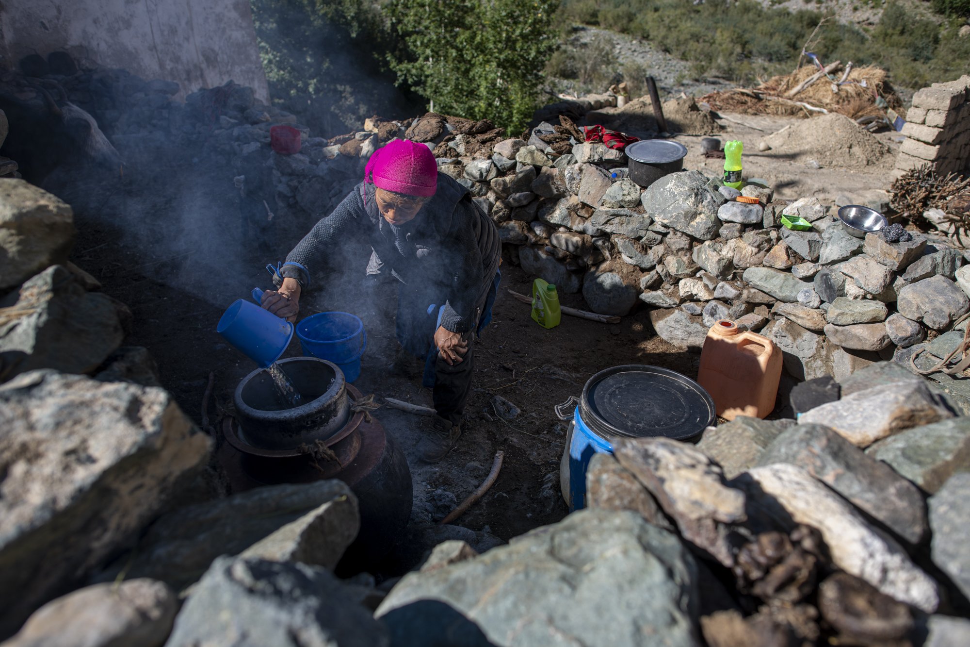 Frau brennt Arak über dem offenen Feuer in Yugar, Zanskar