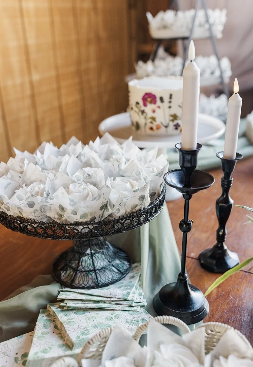 A decorated table with a white cake, candles, and wrapped party favors.