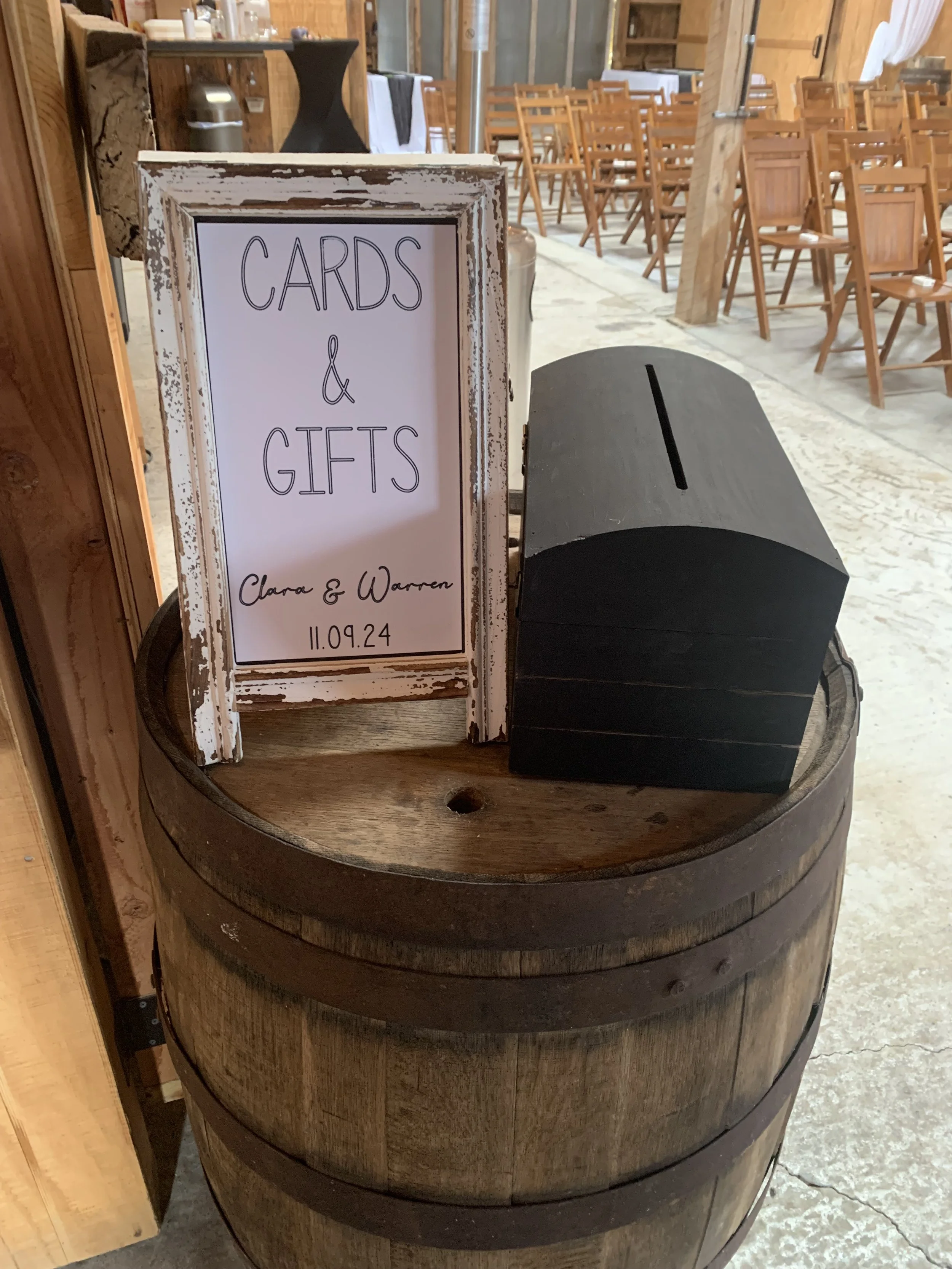 A sign on a rustic wooden barrel indicates a collection box for cards and gifts, with the names Clara and Warren and the date 11.09.24.